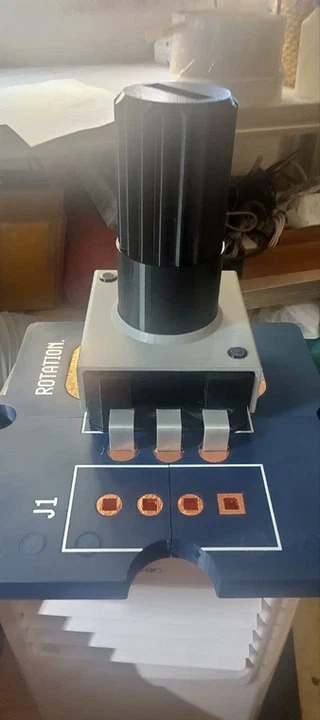 The finished giant rotary sensor, gray body with a large black knurled knob on top and copper-tape connector pads on the blue base plate below.