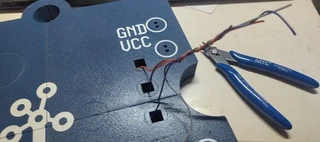 The back of the plate with the wires pulled through their holes, being trimmed to length with flush cutters.