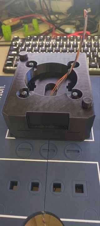 The gray potentiometer body glued onto the base plate, with the wire bundle coming up through its center hole.