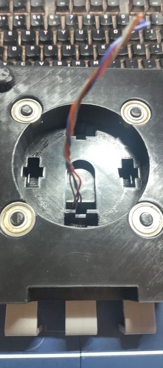 The inside of the potentiometer body, showing four bearing wells with bearings seated in them, and the central slot for the real potentiometer.