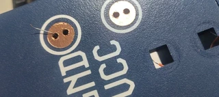 A copper tape circle applied over the GND pad, with the stripped wire poking through and touching the copper.