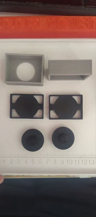 All the 3D printed parts laid out before assembly: the USB-C housing (gray), the chip package cover (gray), two button frames (black), and two button caps (black).